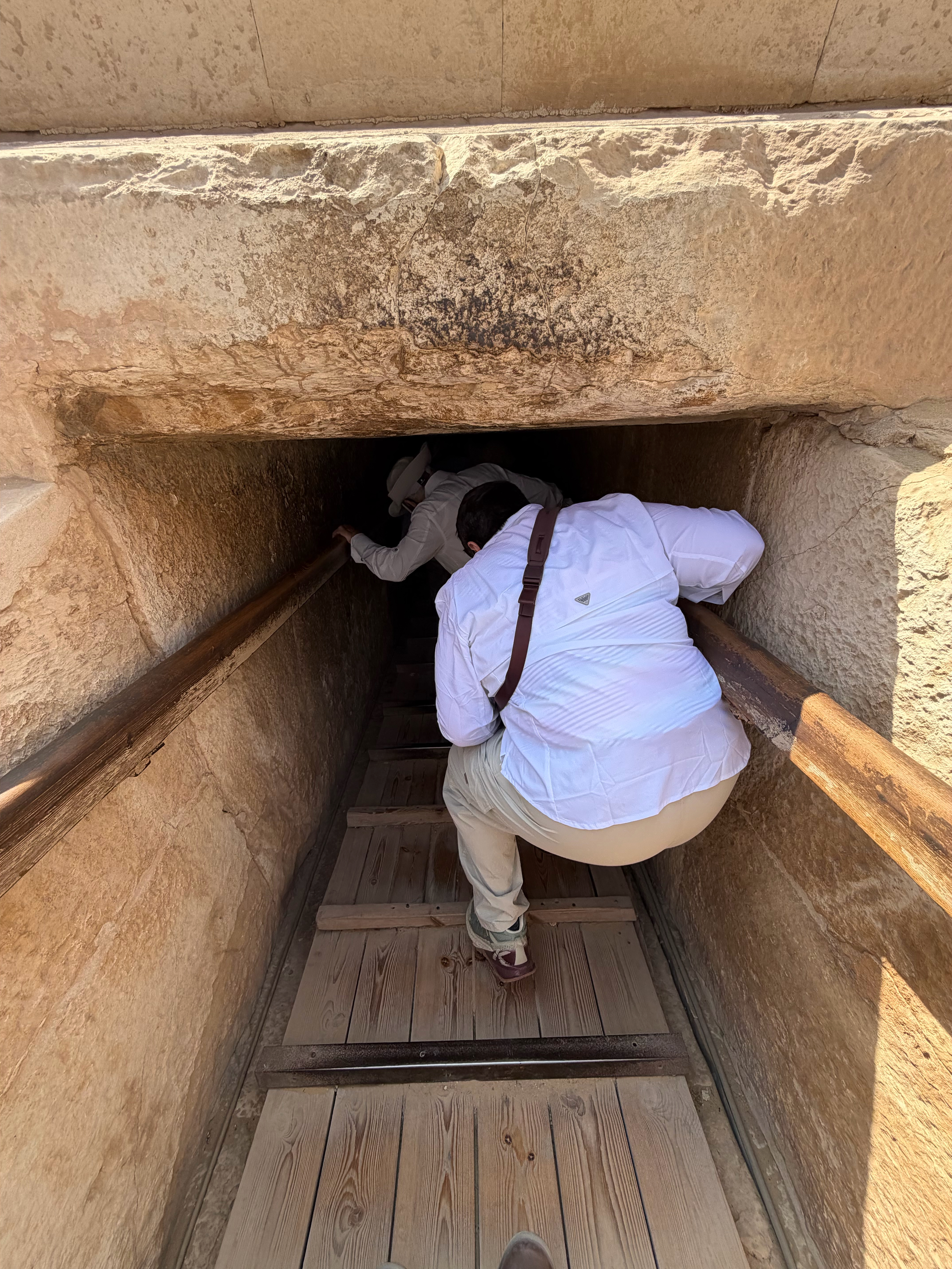 Noel hunched over going into the tunnel down to the burial chamber. 